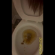 Emi stands over the toilet in a red top on her period, twerking her bare ass as she squirts diarrhea into the bowl, then shows the bowl and smiles into the camera. Vertical format video. Over 12 minutes.
